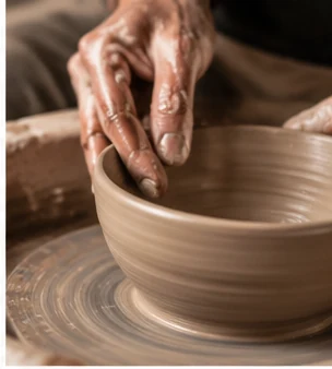 Hands shaping a ceramic piece on a potter’s wheel.